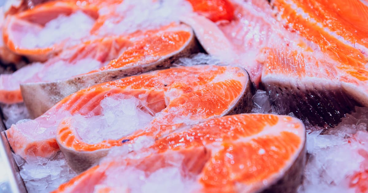 Filete de salmón fresco sobre hielo en un mercado de mariscos, mostrando su color vibrante y textura jugosa, ideal para platos saludables y nutritivos.